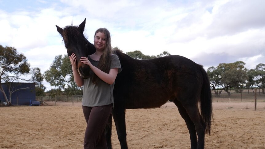 15 year old girl standing proudly next to her horse