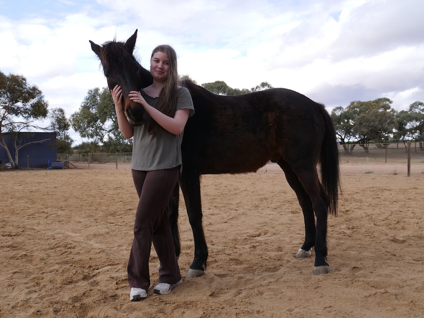 15 year old girl standing proudly next to her horse