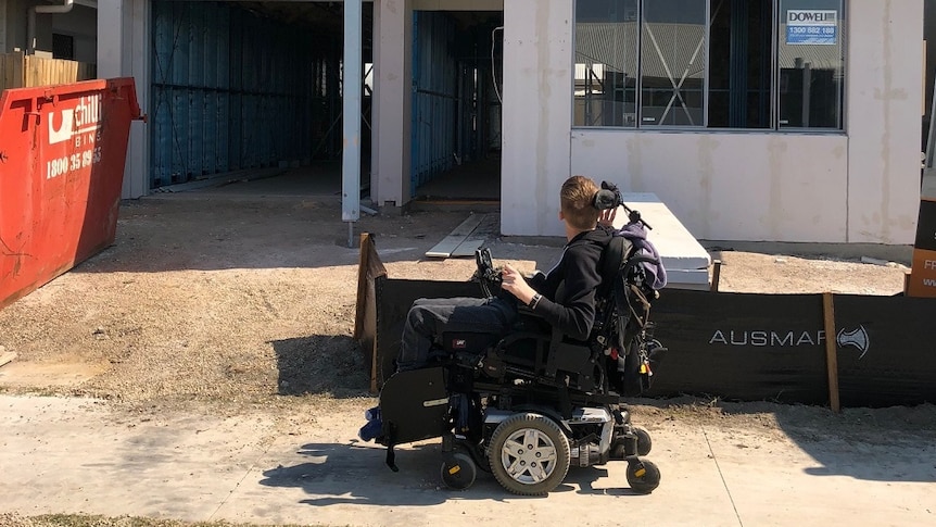 A man in a wheelchair outside a new house under construction