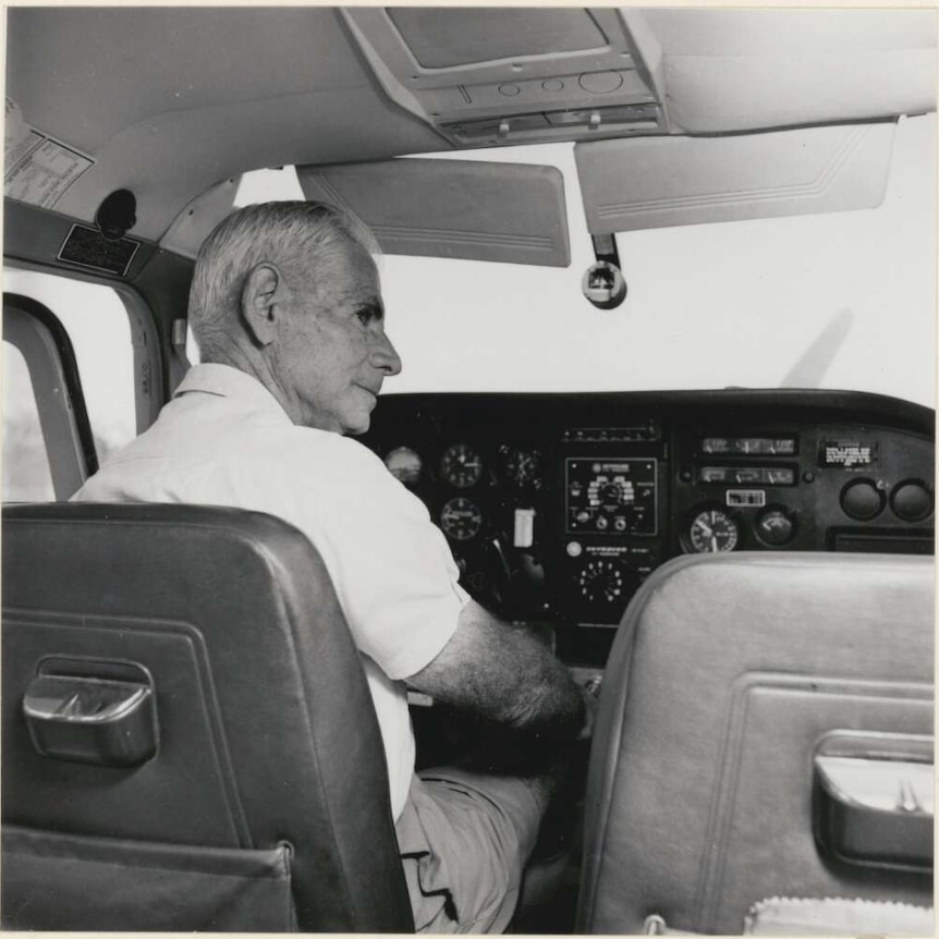 Elderly man sits in the cockpit of a small aeoplane, looking sideways