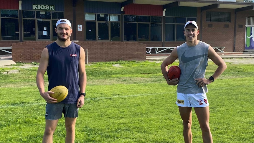 Two AFL players at a football oval in regional Victoria
