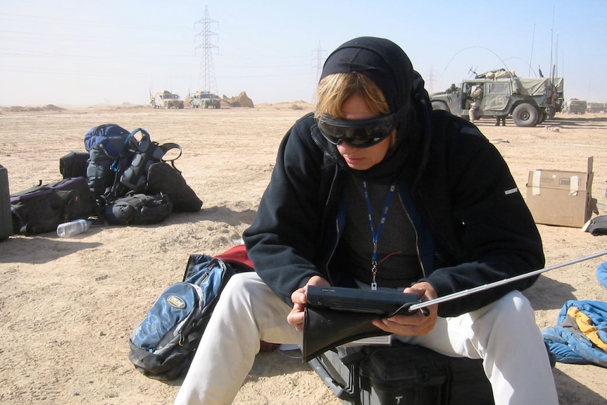 Liz Jackson wearing sunglasses as she stares at a device