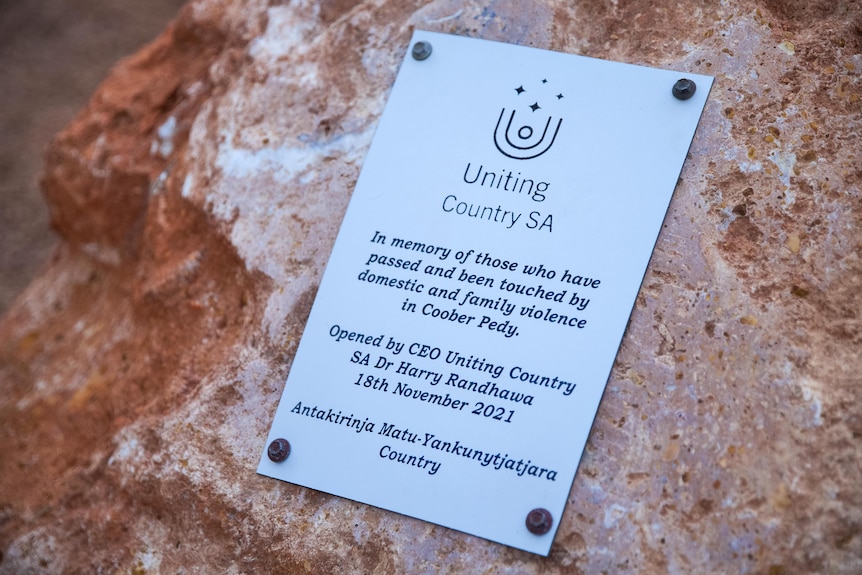 A plaque mounted on a rock commemorating those who have been touched by domestic violence in Coober Pedy