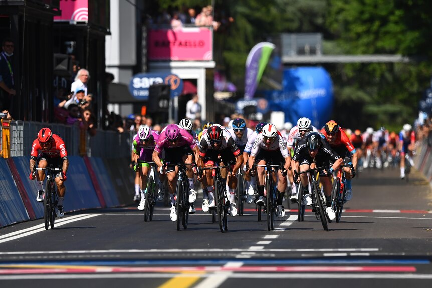 Caleb Ewan, a la izquierda, monta su bicicleta en un sprint masivo