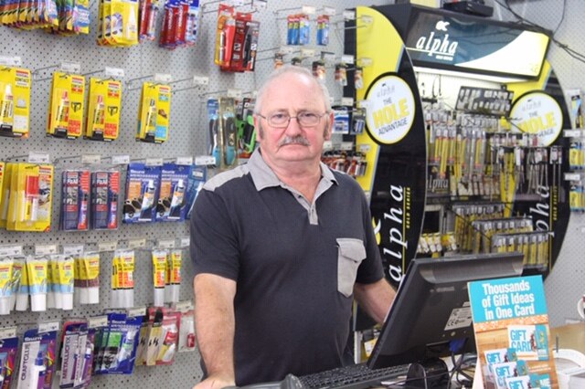 A man stands at the counter of a hardware store