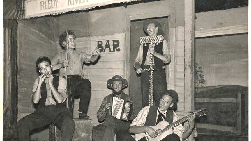 BW photo of five musicians playing on a stage sign 'reedy river'