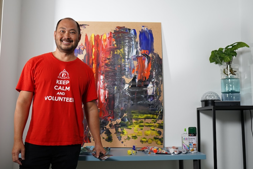 A man stands in his home in front of a painting.