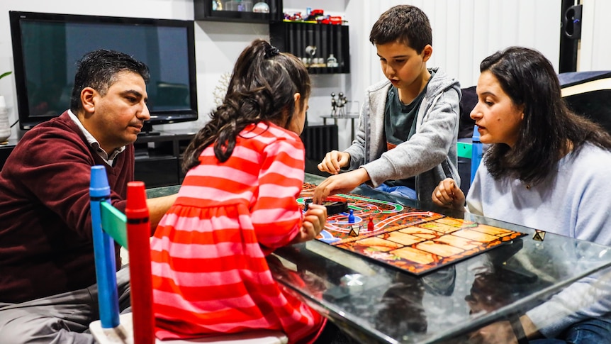 a family sits around a table playing a board game