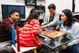 a family sits around a table playing a board game