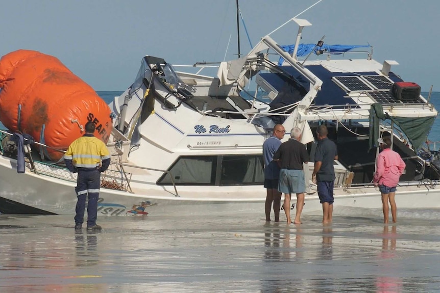 Image of a damaged boat sitting in low water off the coast of Cable Beach.