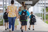 Parent walks children in school uniform into a school, west of Brisbane.