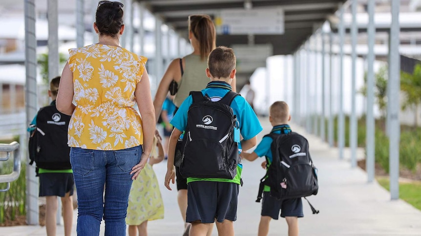 Parent walks children in school uniform into a school, west of Brisbane.