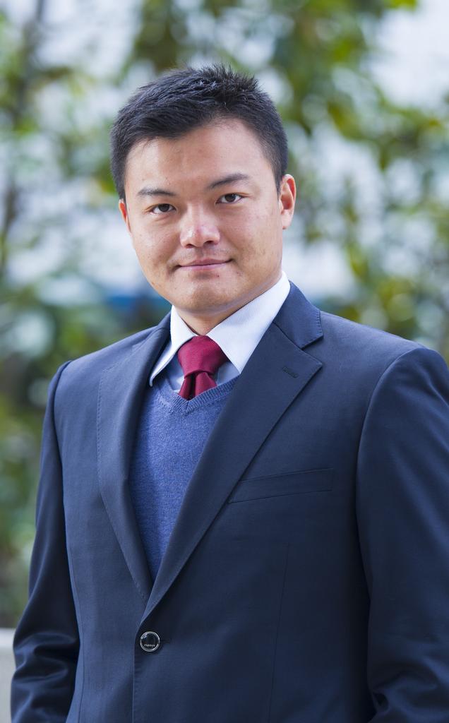 一名男子穿着西服站在草地前