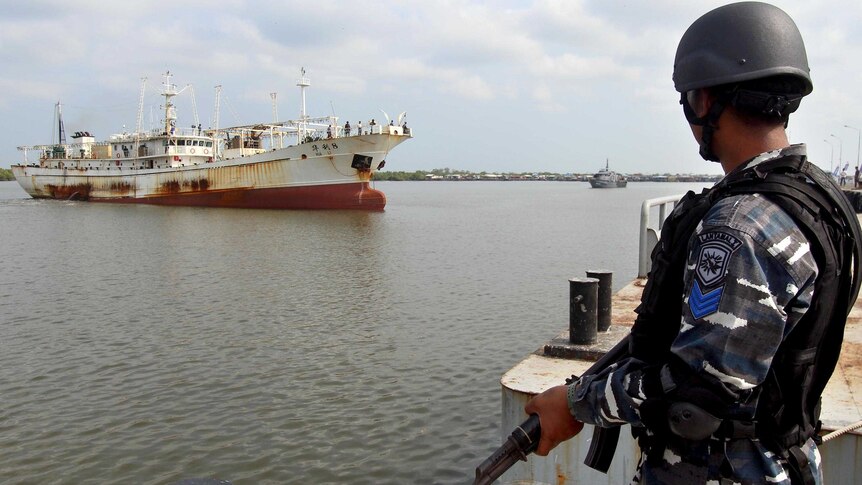 A member of the Indonesian navy watches the Chinese trawler, moored offshore.