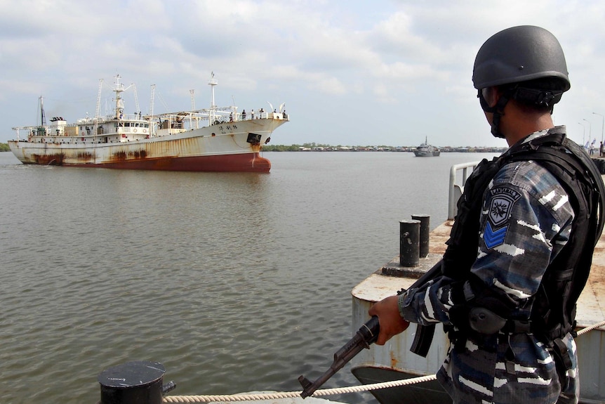 A member of the Indonesian navy watches the Chinese trawler, moored offshore.