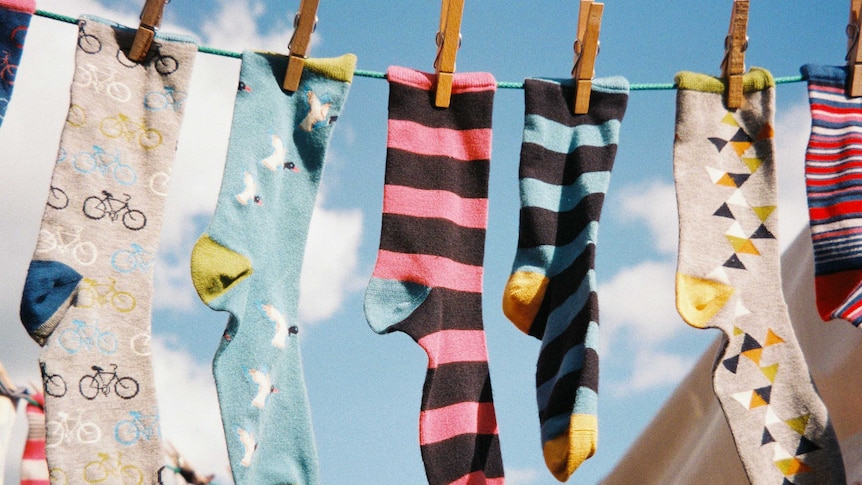 Socks hang outside on a clothes line on a sunny day.