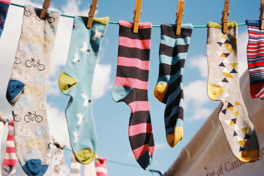 Socks hang outside on a clothes line on a sunny day.