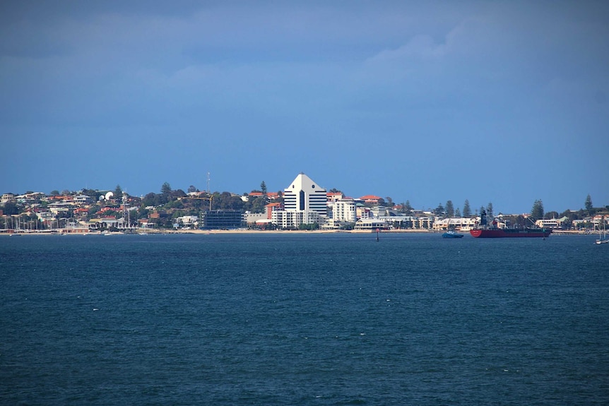 A built up town skyline taken at a distance across a blue ocean