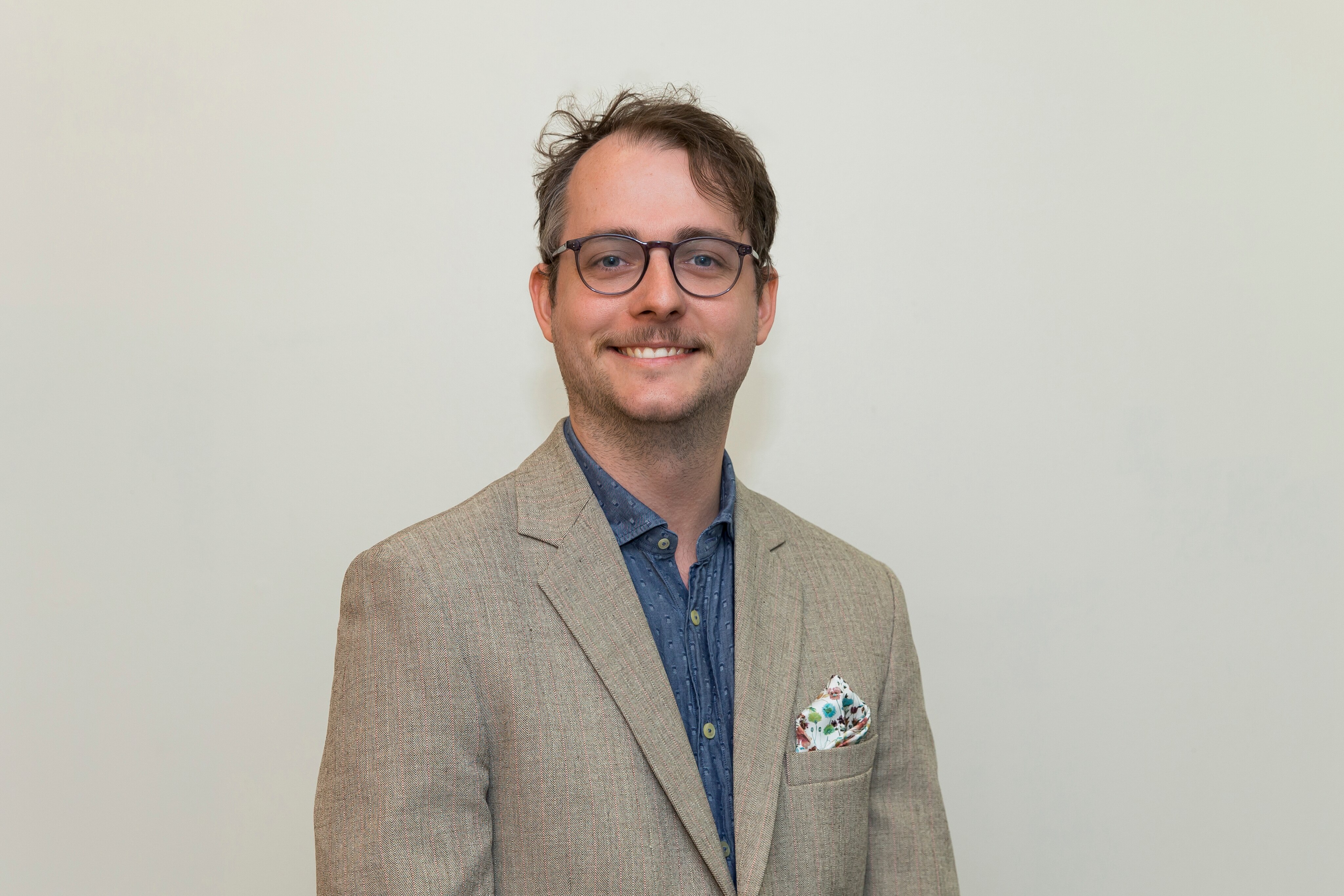 Un hombre con gafas sonríe a la cámara