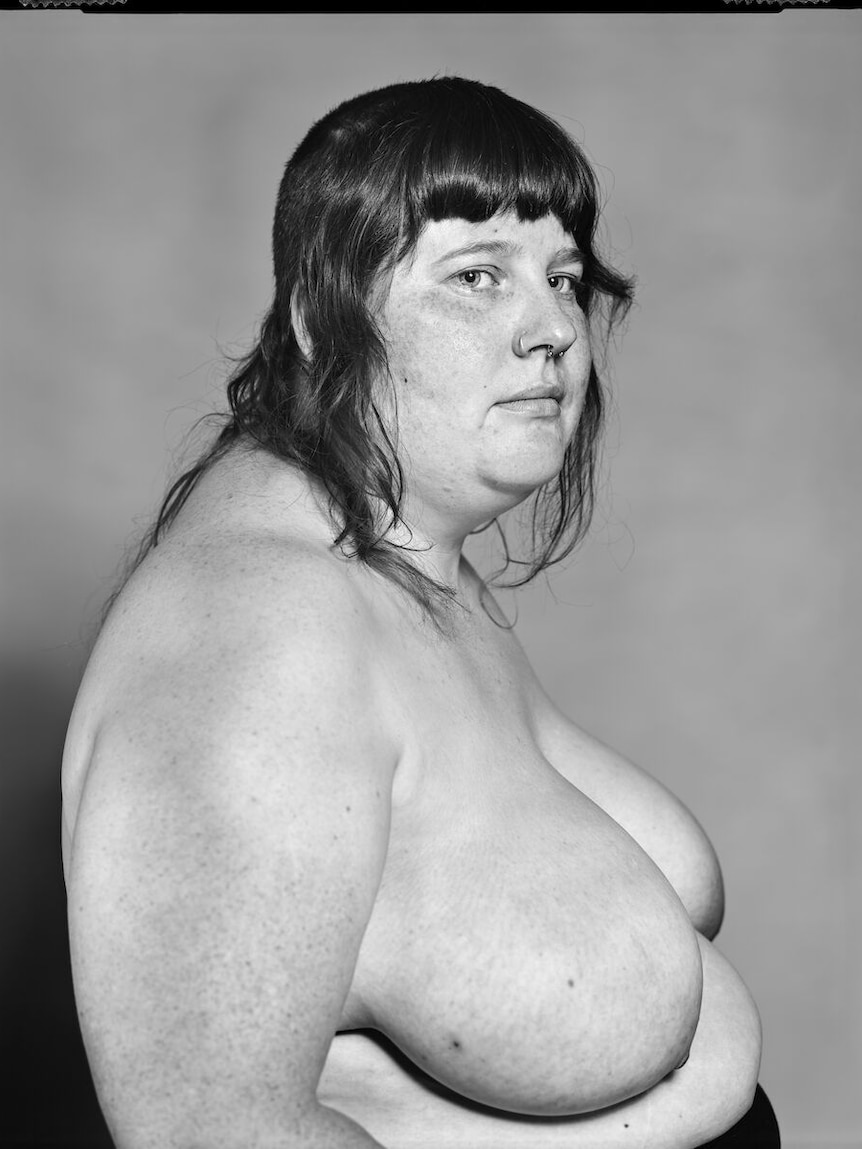 A black and white photo of a topless person from their right side.