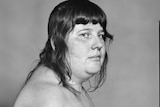 A black and white photo of a topless person from their right side.