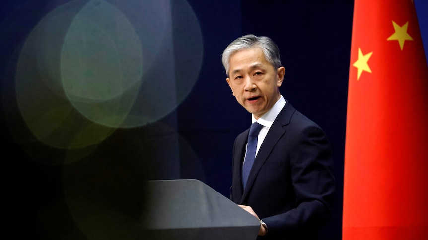 China's foreign ministry spokesman Wang Wenbin speaks during a press conference in 2020, flanked by a Chinese flag.