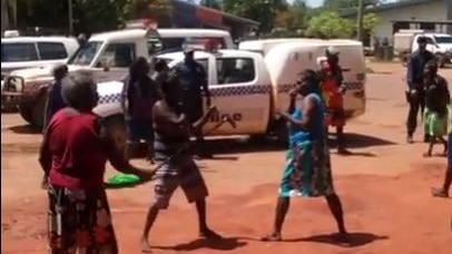 Police watch on while two women fight in Aurukun.
