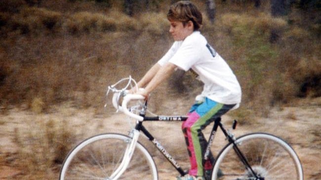 A young girl riding her bike on a dirt track.