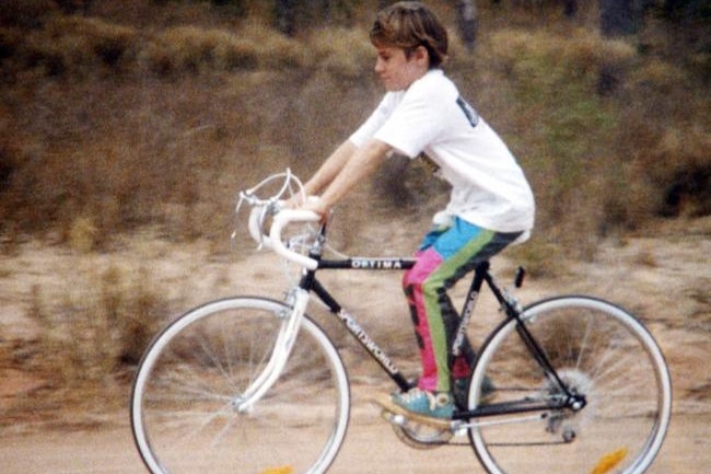 A young girl riding her bike on a dirt track.