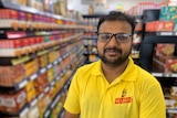 An Indian man in glasses stands in a shop aisle