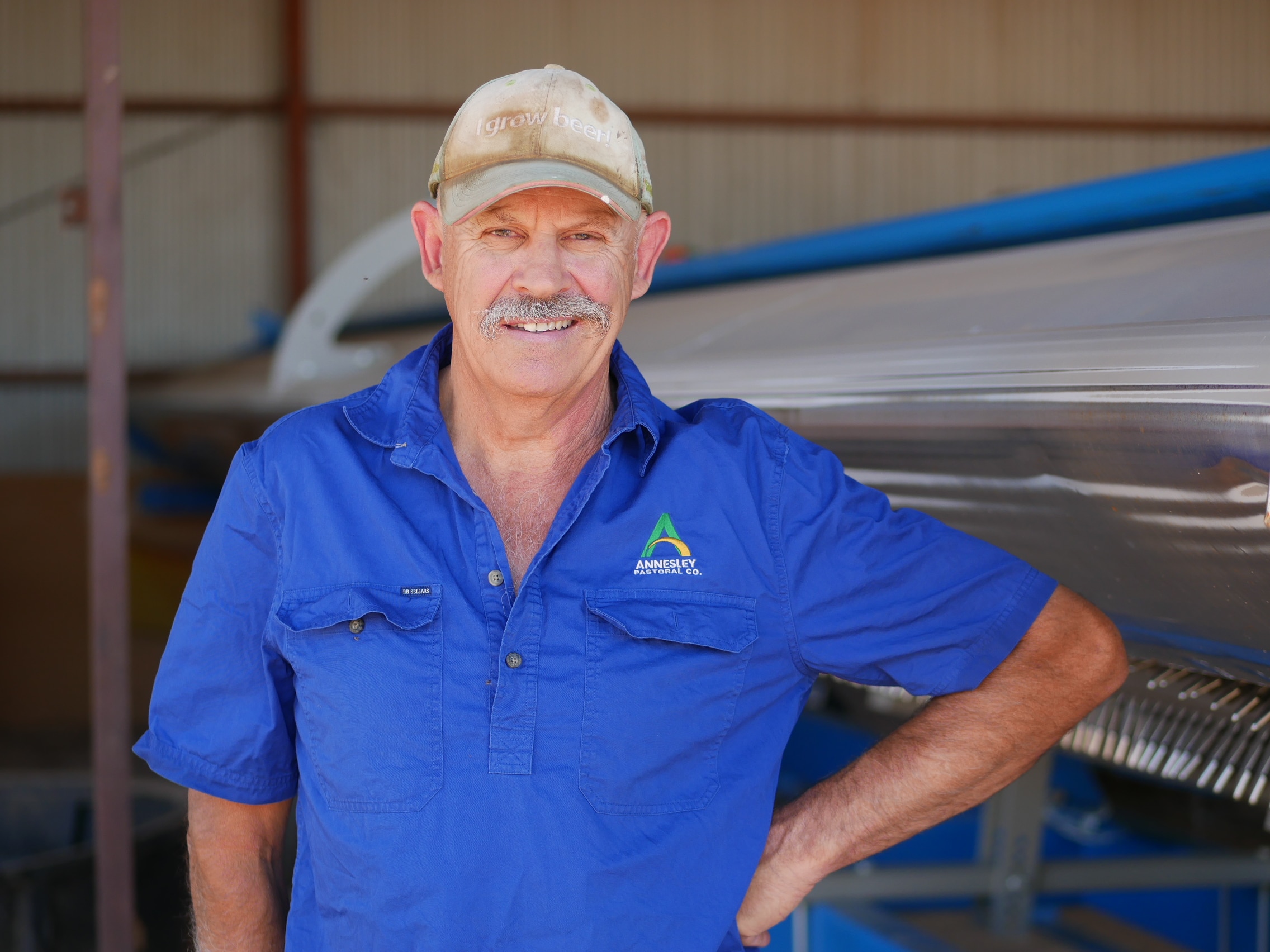 Un hombre con una camisa azul y bigote sonríe a la cámara