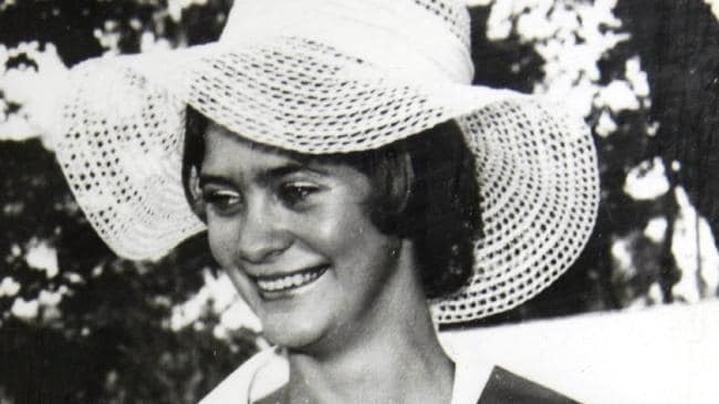 A black and white photo of a young woman with dark hair wearing a large white hat and smiling broadly.