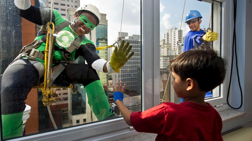 Window cleaners wearing superhero costumes greet a patient at a children's hospital in Sao Paulo.