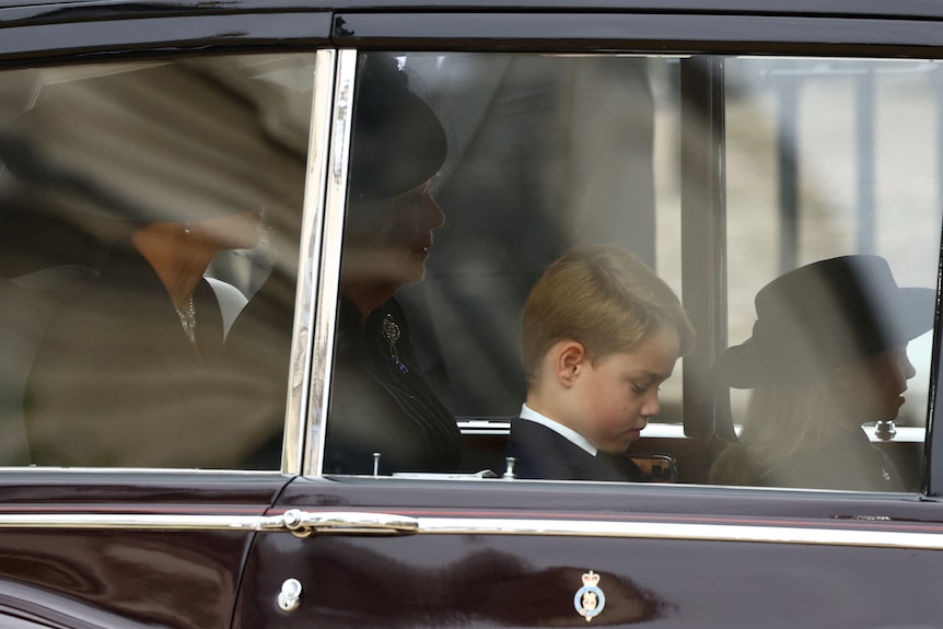 Prince George and Princess Charlotte seen through windows of a car