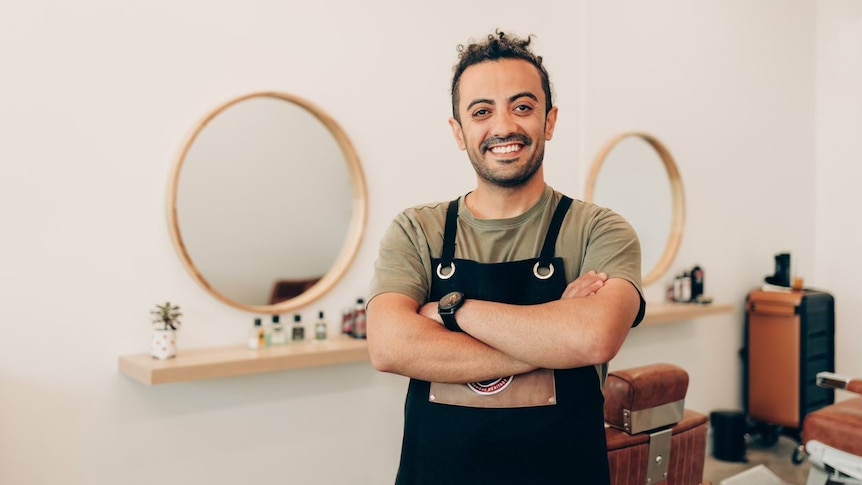 Smiling man in his barber shop, in a story about how to make a good first impression when starting new job.