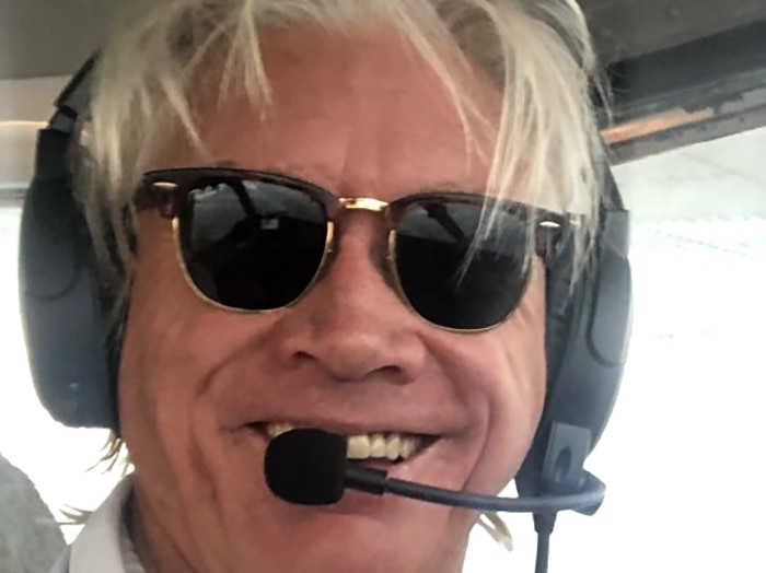 A man smiling from the cockpit of a plane