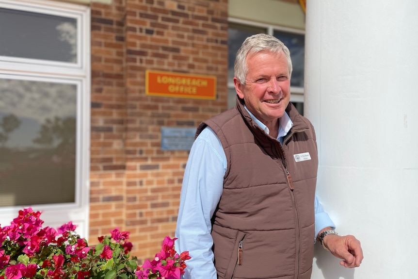 Man in a brown vest smiles at camera.