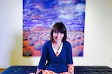 Sarah Brown sitting in front of an artwork that she painted