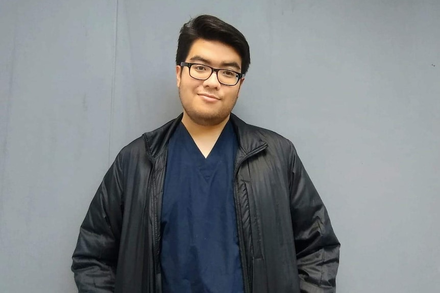 A guy wearing glasses posing with nurse uniform