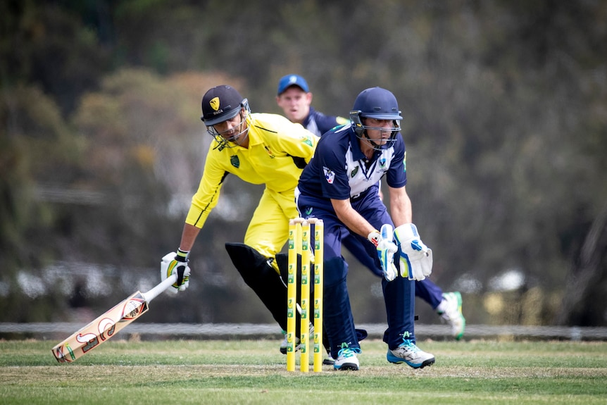 Un joueur de cricket fait son chemin alors qu'un gardien de guichet attend le ballon dans les championnats australiens d'inclusion de cricket. 