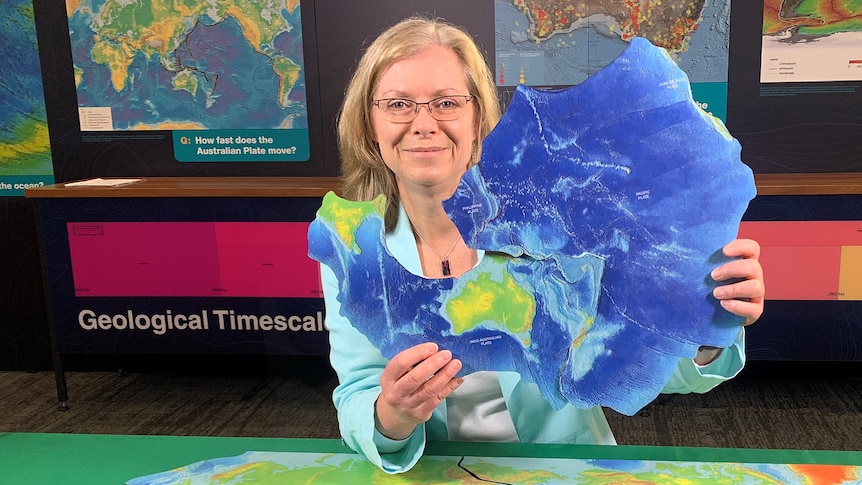 A woman holds up an irregular shaped piece of the Earth's surface