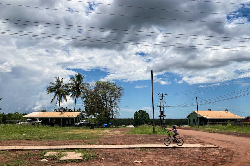 A streetscape with a young boy riding a push bike.