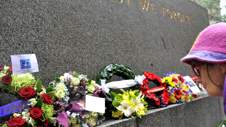 A member of the public looks at the flowers and wreaths laid on the Cenotaph in Martin Place.