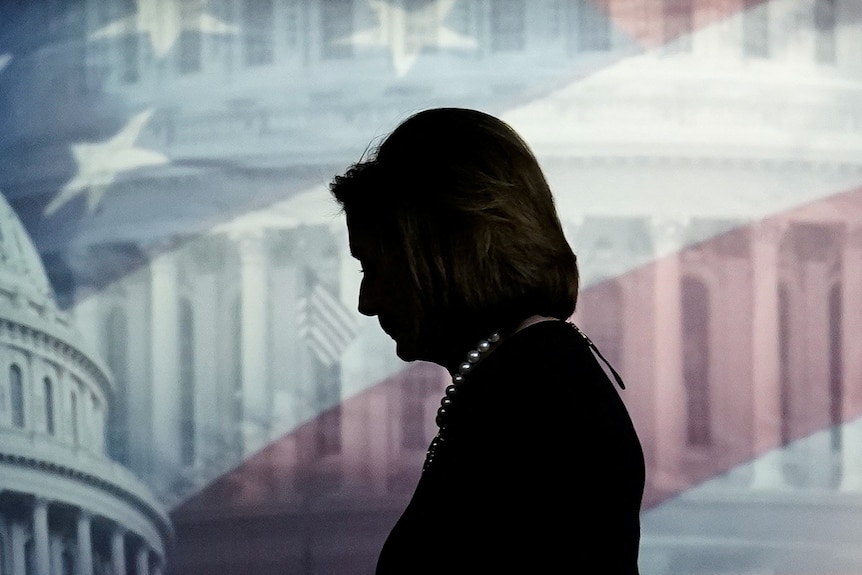 Nancy Pelosi's profile in silhouette behind a screen featuring the US Capitol dome and a US flag 