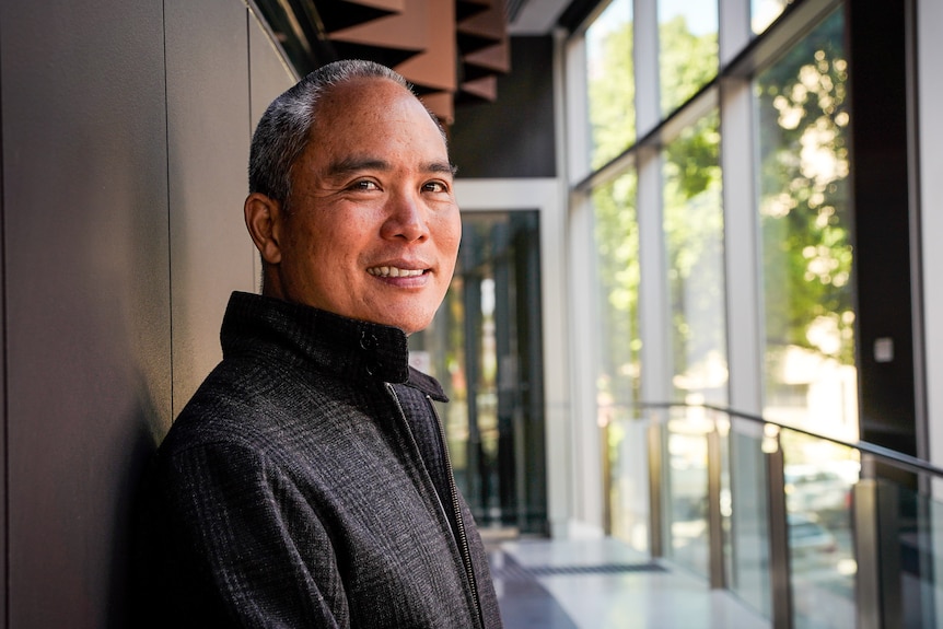 Joo-Cheong Tham smiles, as he stands in a sunlit corridor.