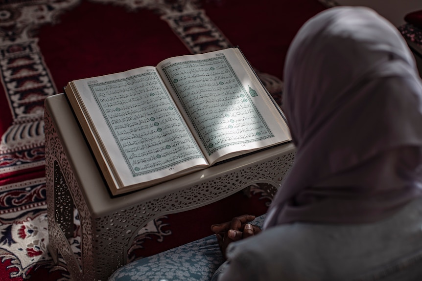 A woman in a hijab reading the Koran.
