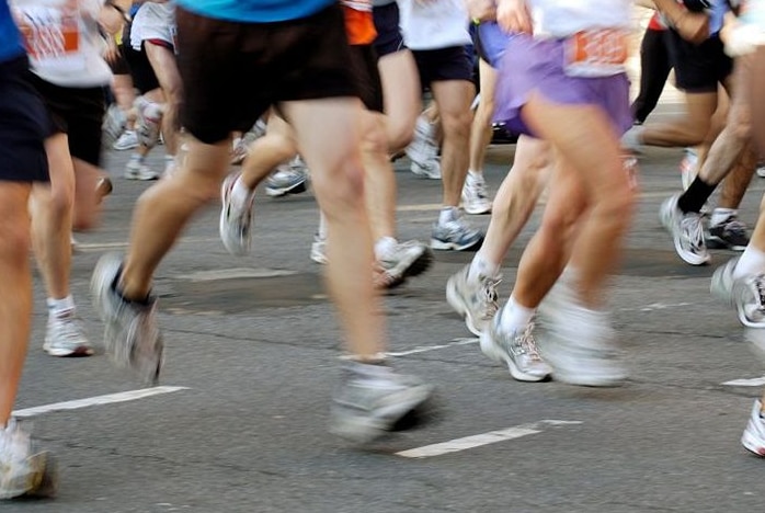 Lower half of body of group runners on a road with legs slightly blurred