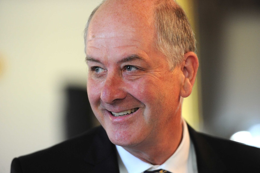 A smiling, older, balding man in a suit and tie.