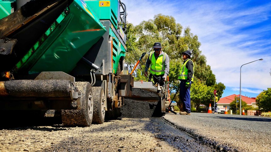 Road workers lay asphalt on a Canberra street.