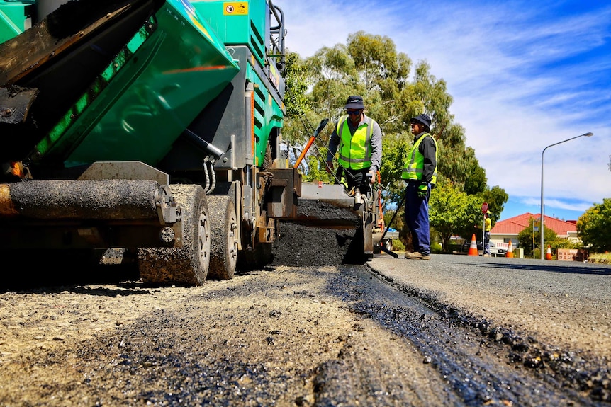 Road workers lay asphalt on a Canberra street.